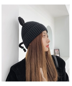 Detail of black knit beanie featuring cute cat ears and side braid decoration