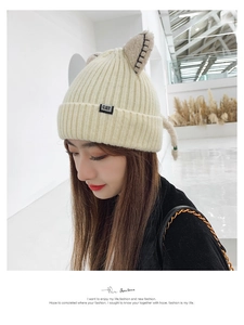 Detailed shot of beige knit beanie featuring cute cat ears and a small black CAT label