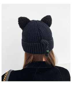 Detail of black knitted beanie with cute cat ears and pom-pom tail detail on the back