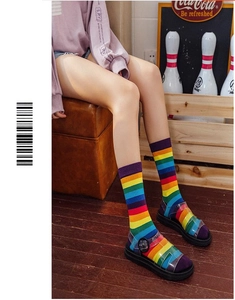 Detail view of rainbow striped knee high socks featuring vibrant colors on a model