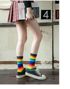 Side view of rainbow striped crew socks paired with a plaid skirt and canvas shoes