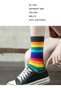 Detail of vibrant rainbow striped high socks paired with black canvas sneakers for women
