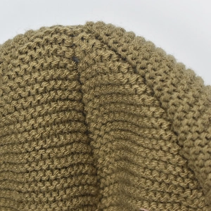 Macro detail of olive green chunky knit hat showing thick yarn texture and stitched seam