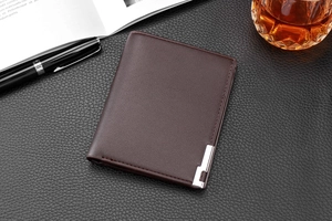 Deep brown leather wallet with metallic detail on textured background with pen and glass