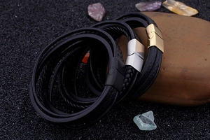 Detailed macro view of woven multi-layer leather bracelets with branded metal magnetic clasps