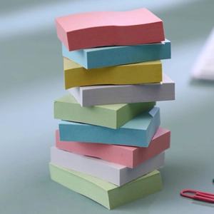 Stack of colorful mini sticky notes in pastel colors on a neutral background