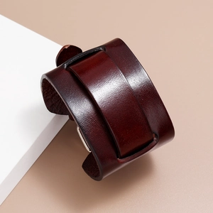 Detailed close-up of a wide vintage dark brown leather bracelet on a white display block