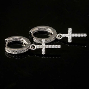 Macro shot of silver hoop earrings with zircon-studded cross pendants on black surface