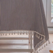 Detail of striped table runner with white decorative tassels and hollow embroidery