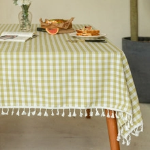 Close-up of light green checkered tablecloth with white decorative fringe tassels
