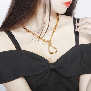 Gold square link necklace with heart pendant and pearl on model featuring OT toggle clasp
