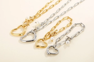 Flat lay of gold and silver square link jewelry sets with heart and pearl charms