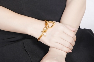 Close-up of golden chain bracelet with heart-shaped OT buckle and pearl pendant detail