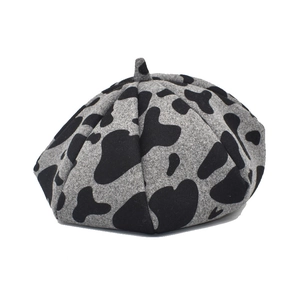 Close-up of vintage wool beret featuring a gray and black cow print pattern texture