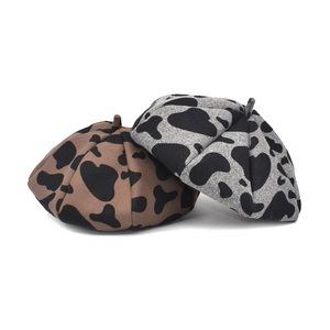 Retro cow print wool beret hats in brown and grey with minimalist white background