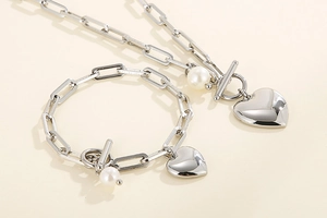 Détail d'ensemble collier et bracelet à maillons trombone avec pendentifs cœur et perle