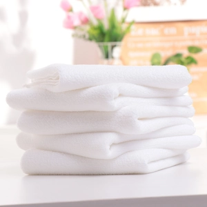 Close-up of soft white absorbent towels neatly stacked in a bright hotel bathroom setting