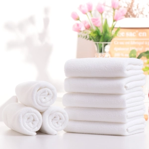 Premium absorbent white cotton hotel towels set neatly folded and rolled on table