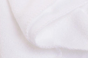 Macro shot of white hotel towel texture showing soft absorbent cotton loops and fine edging