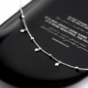 Macro shot of silver clavicle chain with polished round beads and shimmering flat disks