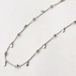Detailed shot of a minimalist silver chain with small round beads and circular pendants