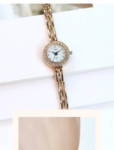 Macro view of gold quartz watch with diamond bezel and metallic chain bracelet strap