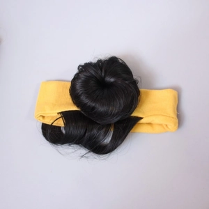 Detail of baby headband with a black curly hair bun and yellow ribbed fabric bow