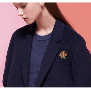 Detail of a gold fish brooch with crystals pinned on a navy wool blazer lapel