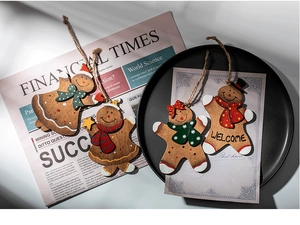 Detail of hand-painted wooden gingerbread man ornaments set on a rustic tray and newspaper