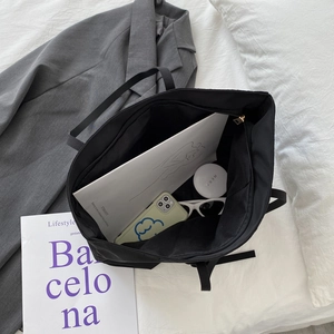 Large black nylon tote bag with gold zipper showing spacious interior for daily essentials