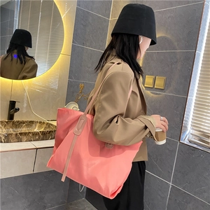 Detailed side view of large pink nylon tote bag on shoulder with casual outfit