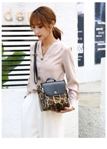 Detail of leopard print handbag with black leather panel and gold D-ring hardware