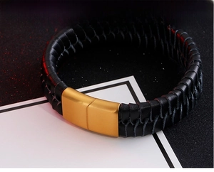 Detail of black woven leather bracelet with matte gold magnetic clasp and tough texture