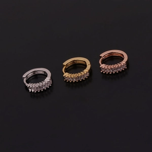 Dettaglio di tre orecchini a cerchio geometrici con zirconi in argento, oro e rosa