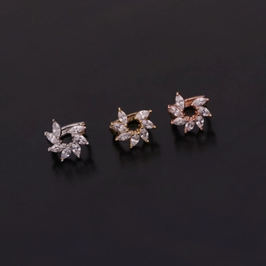 Dettaglio di tre orecchini a fiore con zirconi, finiture in argento, oro e oro rosa