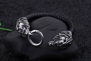 Detailansicht eines schwarzen Lederarmbands mit zwei Löwenkopf-Metallanhängern