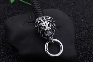 Nahaufnahme von silbernem Löwenkopf an schwarzem Lederarmband auf dunklem Steinhintergrund