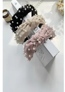 Detailed view of woven knotted headbands featuring white pearls in black, beige, and pink