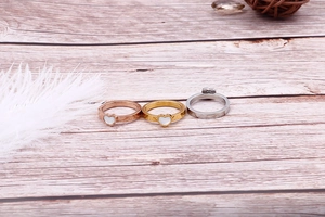 Detailed shot of gold, silver, and rose gold heart rings with pearl inlay on wood