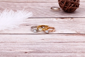 Close-up of three heart-shaped shell inlay rings in gold, silver and rose gold