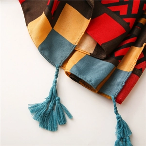 Close-up of geometric color block scarf with decorative blue fringe tassels on textile