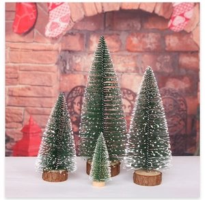 Close-up of four mini snow-flocked Christmas trees with natural wooden bases in a cozy setting