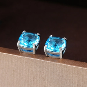 Detailed view of square blue zircon stud earrings in classic four-prong silver setting