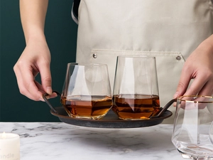 Detail of geometric glass cups with amber liquid on a tray in a home cafe setting