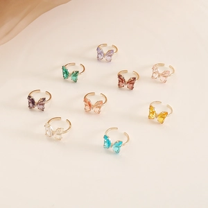 Detailed close-up of multi-color glass butterfly rings with adjustable golden bands