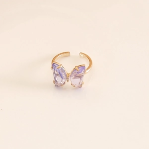 Macro shot of a purple butterfly ring with gold adjustable band on pink background