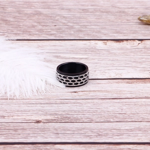 Macro shot of punk style honeycomb hollow design ring on wood texture with feather