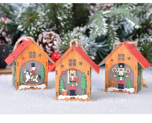 Three wooden nutcracker houses hanging on Christmas tree with pine cones and white snow