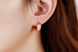 Detailed close-up of gold-plated hoop earrings with three rows of white cubic zirconia