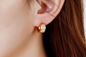 Close-up of gold hoop earrings with double-row white cubic zirconia on female model
